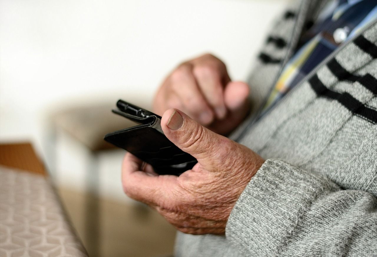 Ein älterer Mann hält ein Smartphone. old man phone