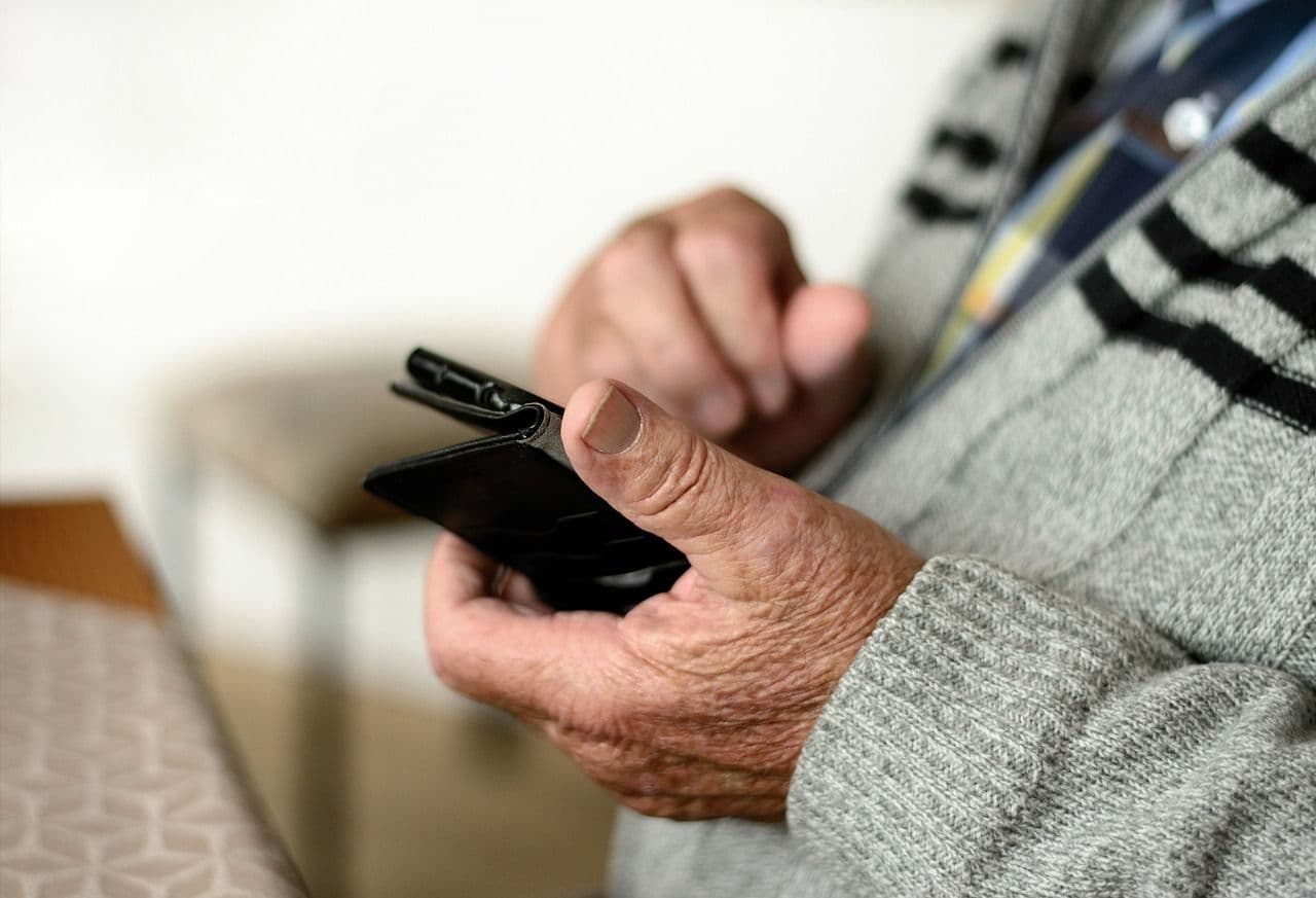 Ein älterer Mann hält ein Smartphone. old man phone